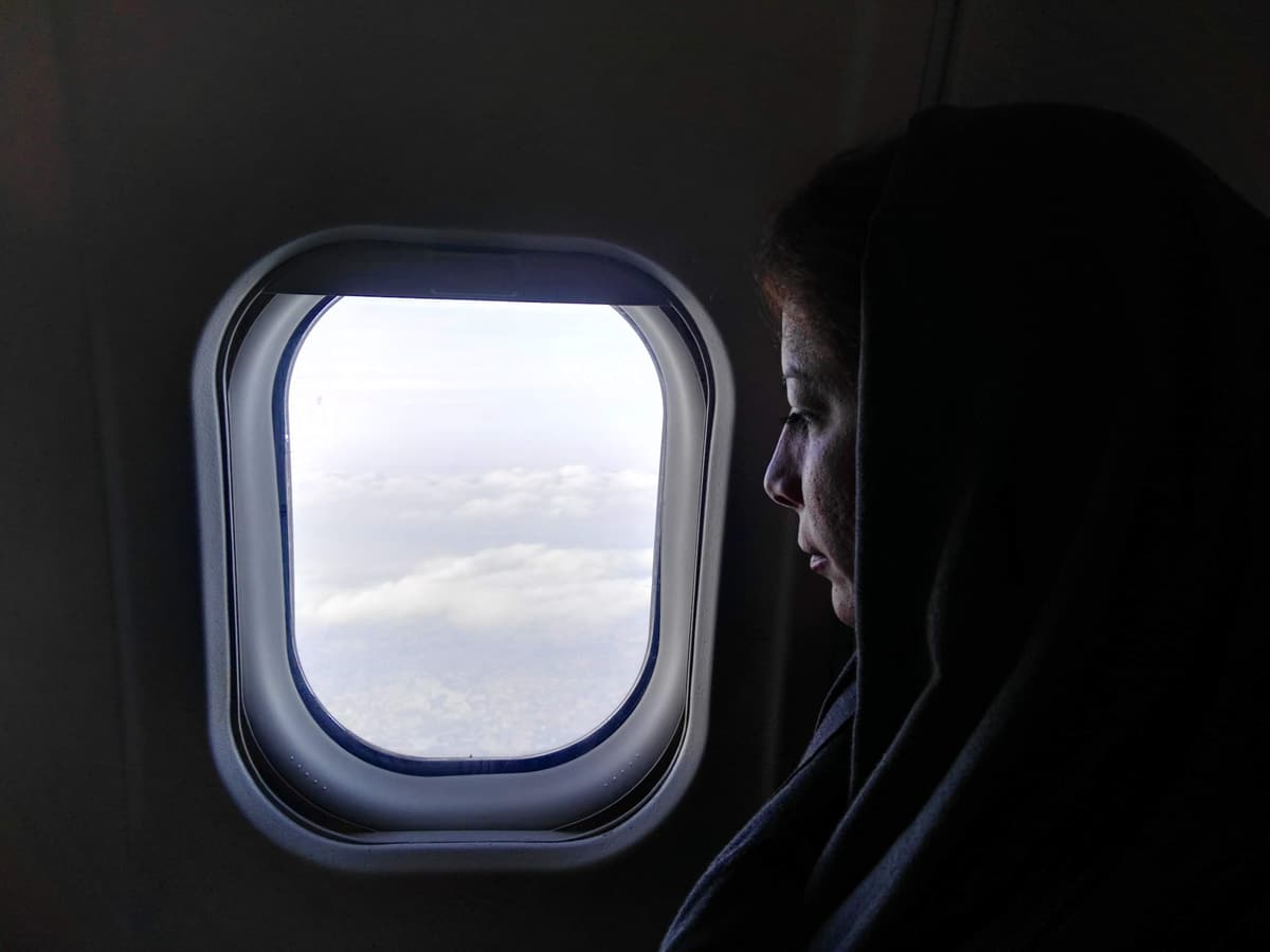 Une voyageuse voilée regarde les nuages par le hublot d'un avion